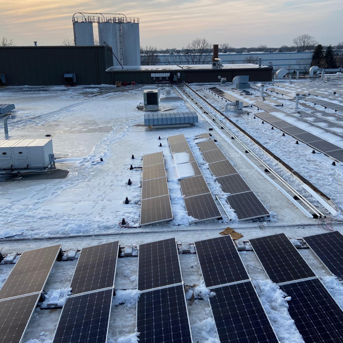 Commercial solar panels on an Alberta rooftop covered in light winter snow